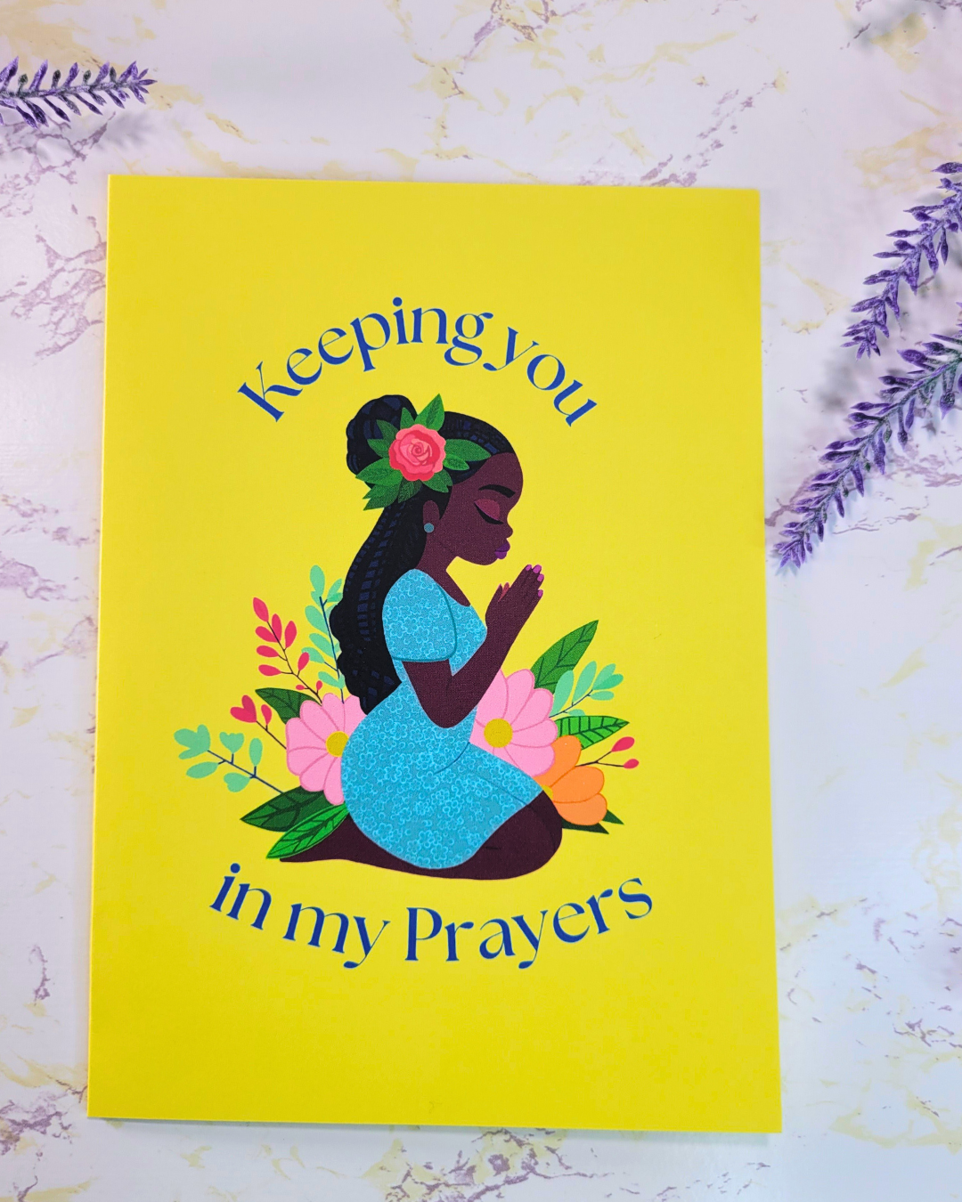 A yellow greeting card with a Black woman kneeling in prayer and the words, "Keeping you in my Prayers"